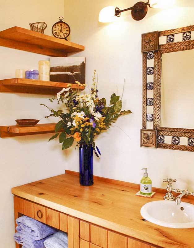 A powder room showcasing floating shelves and a wooden vanity paired with a stylish framed mirror.