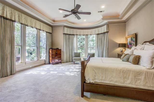 A comfy leather upholstered bed, a large ceiling fan, and a wooden cabinet complete the primary bedroom.