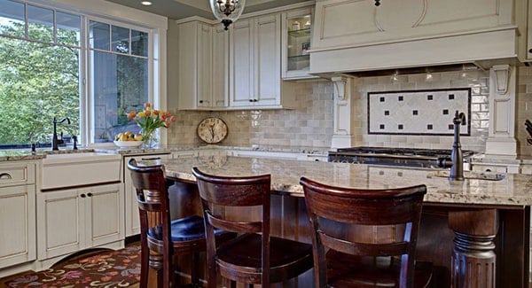 The kitchen is equipped with white cabinets, a farmhouse sink, and an island bar fitted with another sink.