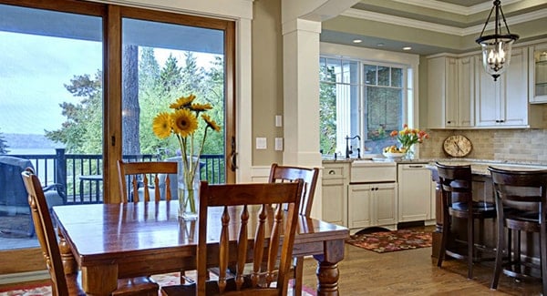 The breakfast nook offers wooden chairs and a square dining table topped with a glass vase.