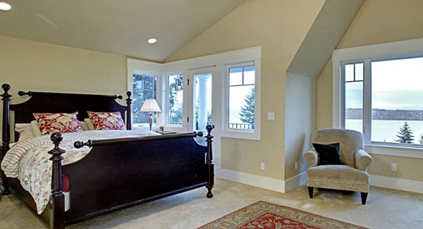 Primary bedroom with a vaulted ceiling and lots of white framed windows that invite an ample amount of natural light in.