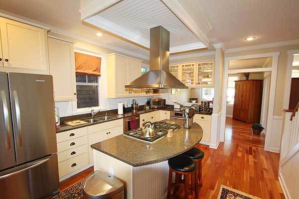 Kitchen with white cabinets, stainless steel appliances, and a curved island complemented with round bar stools.
