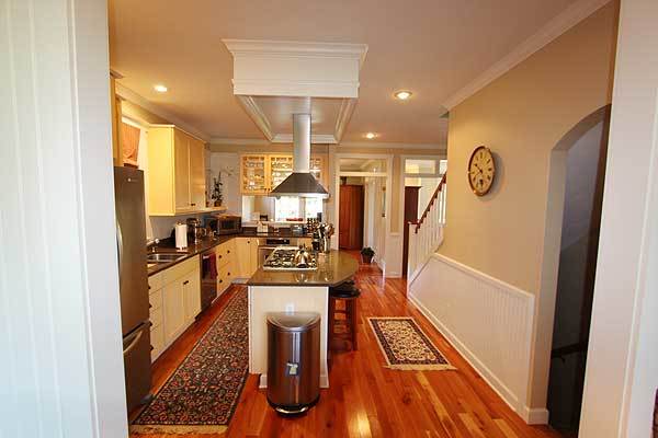 The kitchen has beige walls and a rich hardwood flooring topped with floral runners.