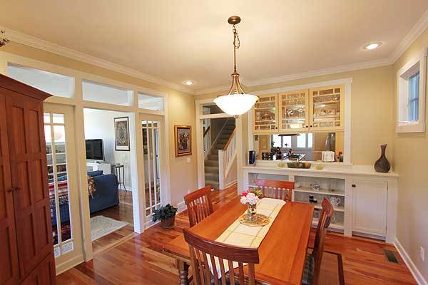 The dining room offers a white buffet bar and wooden dining set illuminated by a glass dome pendant.