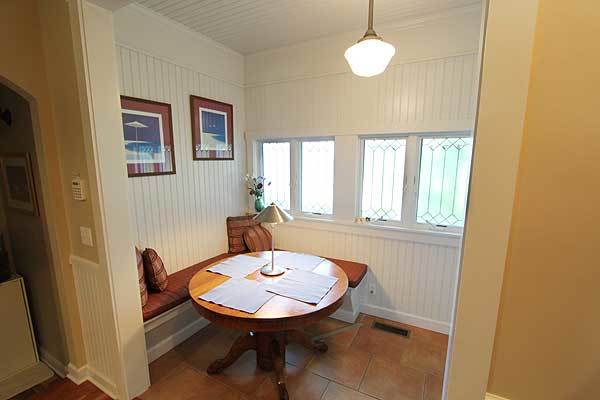Breakfast nook with a round dining table, built-in bench, and a pair of black-framed artworks mounted on the white beadboard wall.