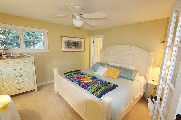 Another bedroom with white furnishings, yellow walls, and beige carpet flooring.