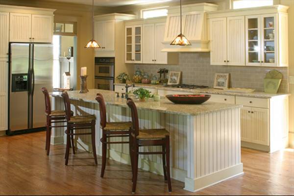 The kitchen is equipped with stainless steel appliances, granite countertops, and beadboard cabinets that match the breakfast island.