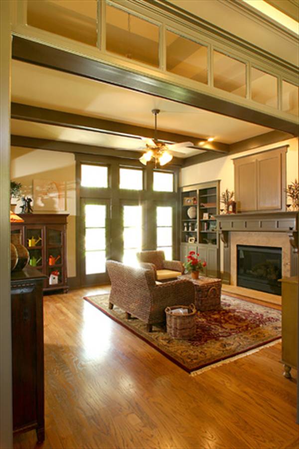 Living room with a glass-enclosed fireplace and rattan seats that are paired with a wicker coffee table over a tasseled area rug.