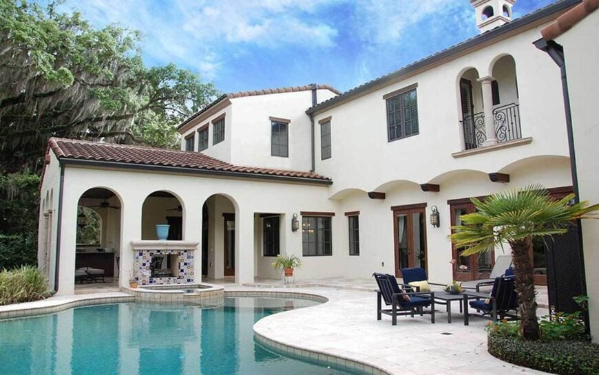 The angled rear view shows the covered lanai, a sun deck, and a freeform pool integrated with a relaxing spa.
