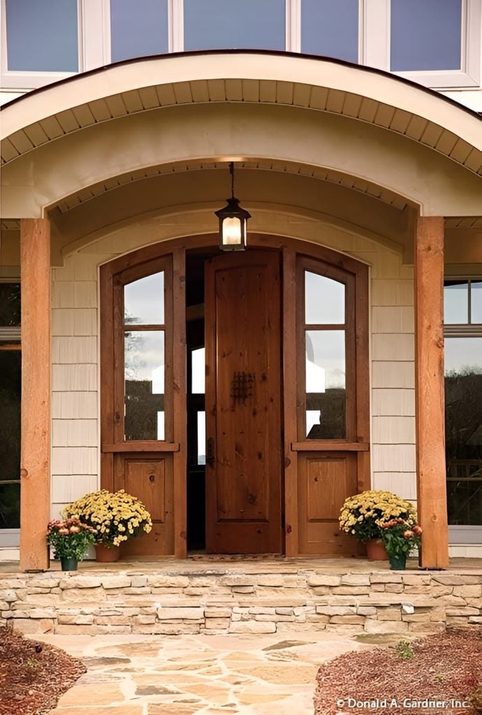 Home entry featuring an arched front door lit by a warm glass sconce hanging from a barrel-vaulted ceiling.