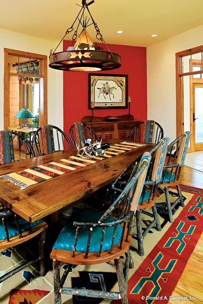 Dining area with a round chandelier, blue cushioned chairs, and a rectangular dining table topped with a striped runner.
