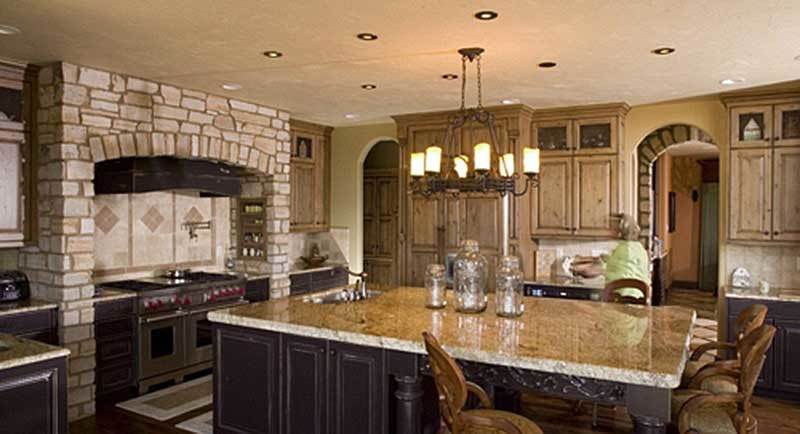 The kitchen offers light wood cabinetry, a cooking alcove, and a granite top island illuminated by a warm glass chandelier.