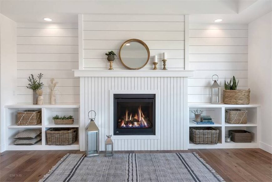 A closer look at the fireplace topped with a round mirror and candle holders.