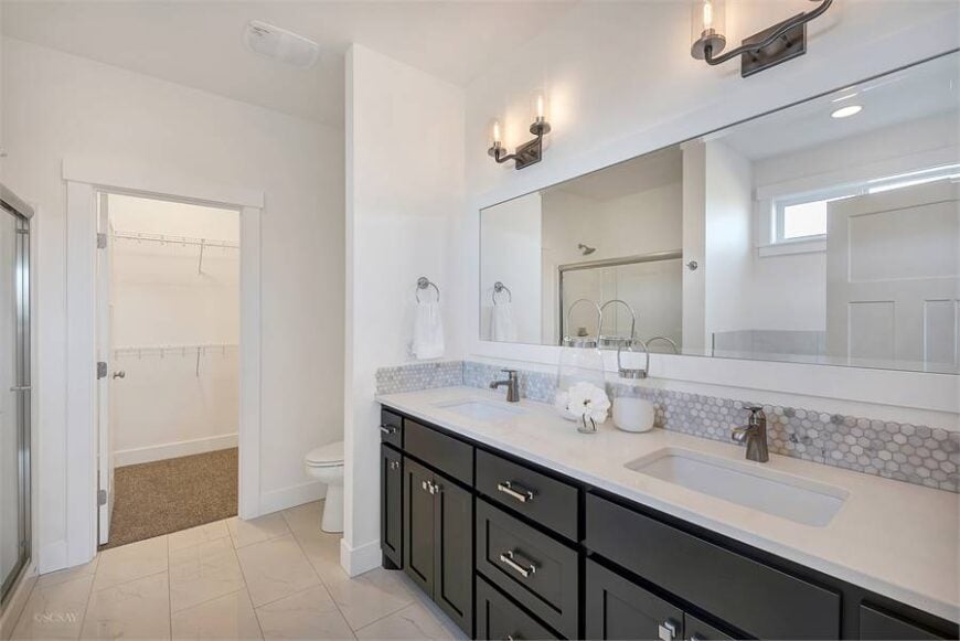 The primary bathroom has a walk-in closet, a toilet, dual sink vanity, and a shower area reflected in the rectangular mirror.