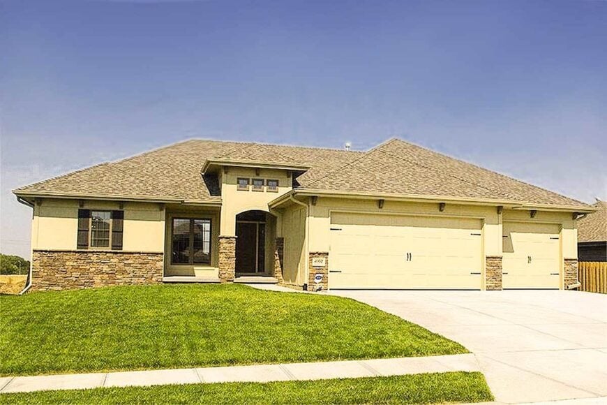 Home's front view showing the three-car garage and a covered front porch topped with transom windows.