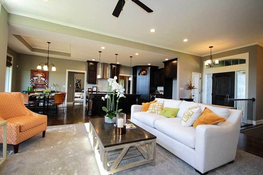 The family room has peach patterned chairs, a rustic coffee table, and a white sofa accented with bright pillows.