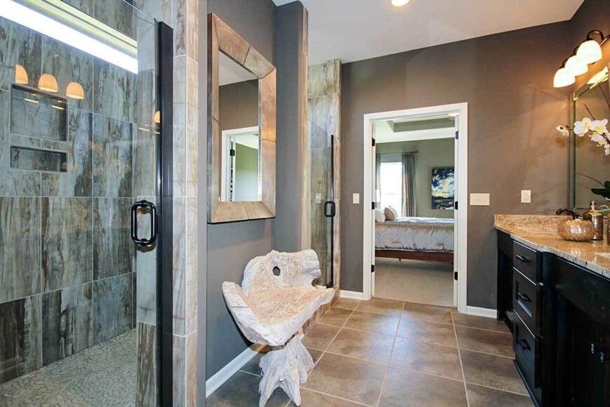The primary bathroom is equipped with a granite top vanity and a walk-in shower complemented with a unique stump bench.