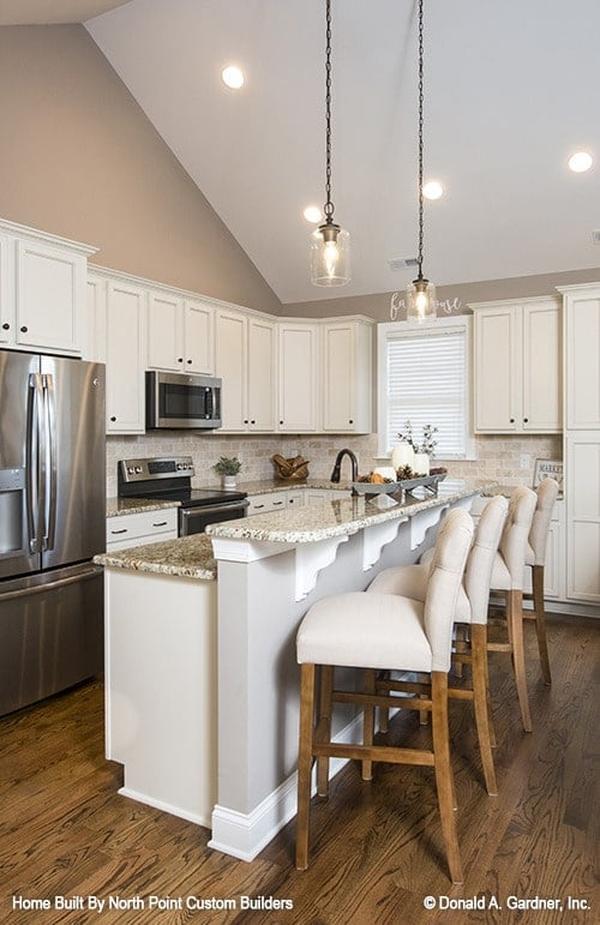 The kitchen is equipped with granite countertops, white cabinetry, stainless steel appliances, and a two-tier island bar.