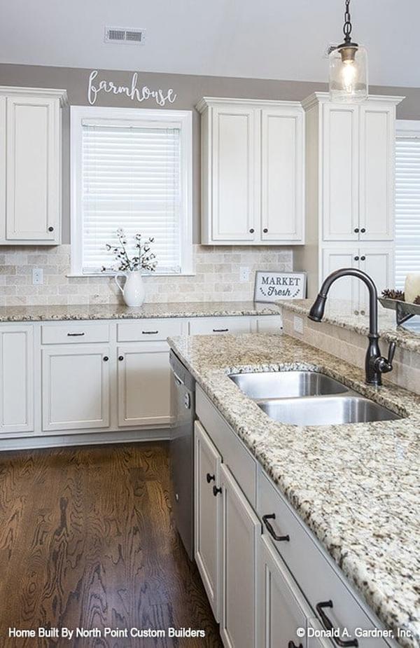 A closer look at the granite top island fitted with a double bowl sink and a wrought iron faucet.