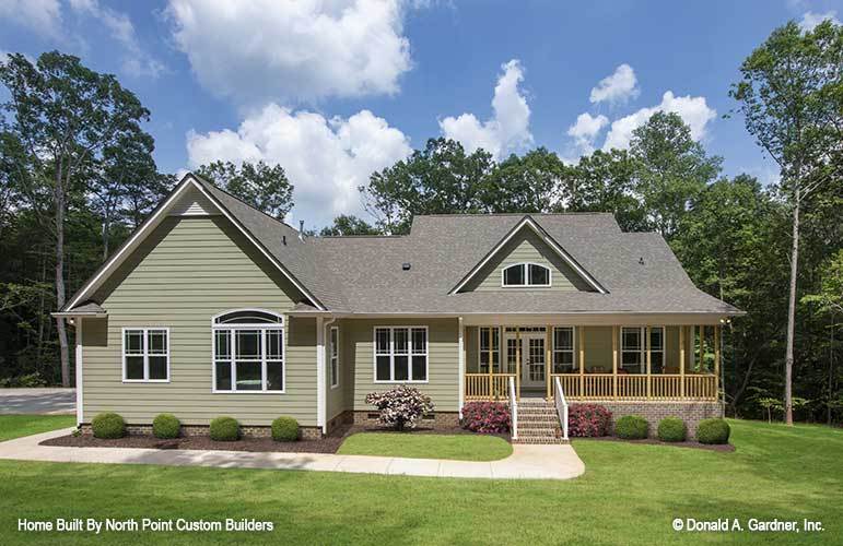 Home's rear view with taupe exterior siding and a covered porch bordered with wooden railings and columns.