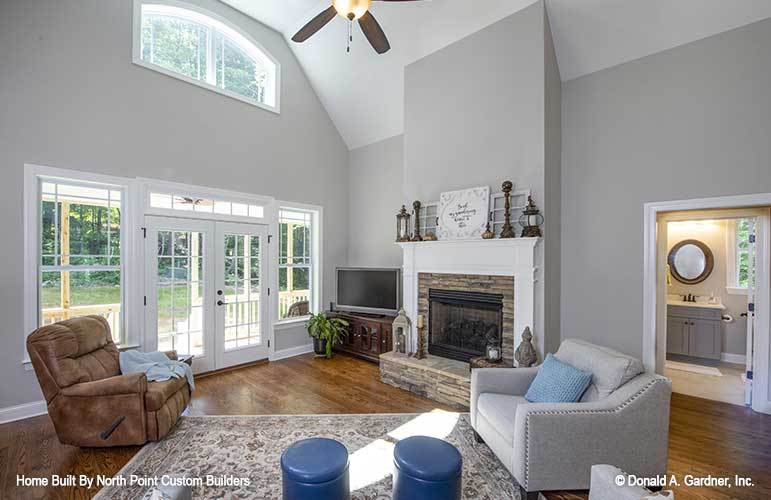 Living room with cozy seats, a patterned area rug, flatscreen TV, and a glass-enclosed fireplace.