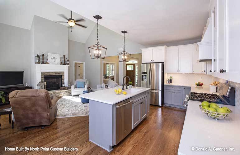 A ceiling fan hanging from the vaulted ceiling along with a pair of caged chandeliers over the kitchen island illuminate the open living space.