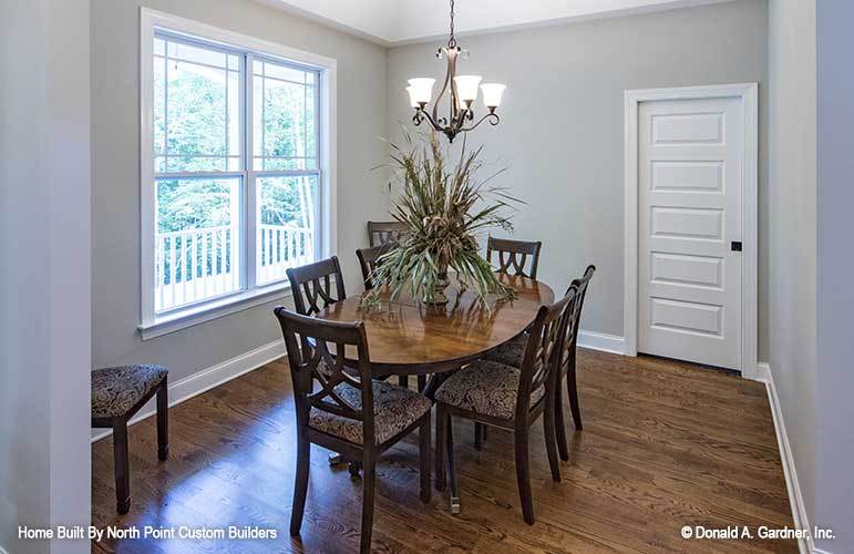 Formal dining room with an ornate chandelier, cushioned chairs, and an oval dining table topped with a lovely vase.