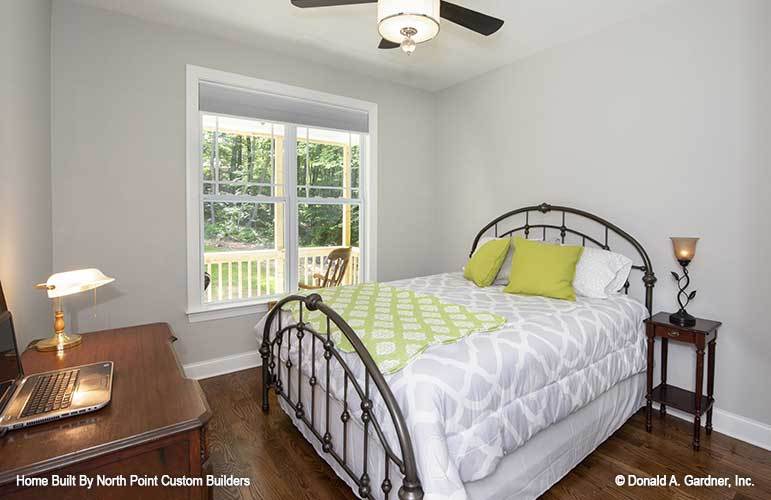 This bedroom has a wooden desk and an ornate metal desk complemented with a dark wood nightstand.