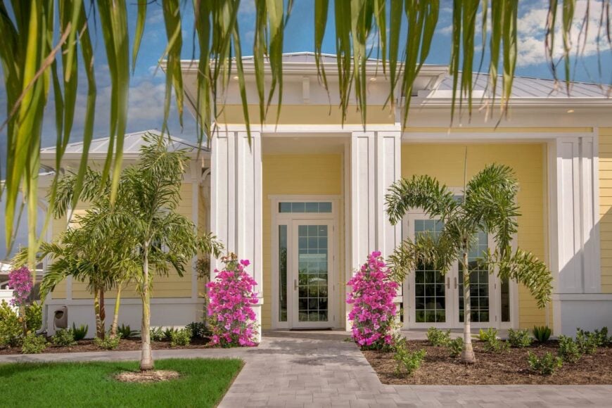 Home entry featuring a glass front door and decorative columns accentuated with colorful flowers.