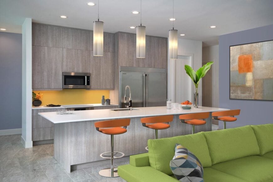 The kitchen has sleek wooden cabinetry, stainless steel appliances, and a breakfast island well-lit by cylindrical pendants.