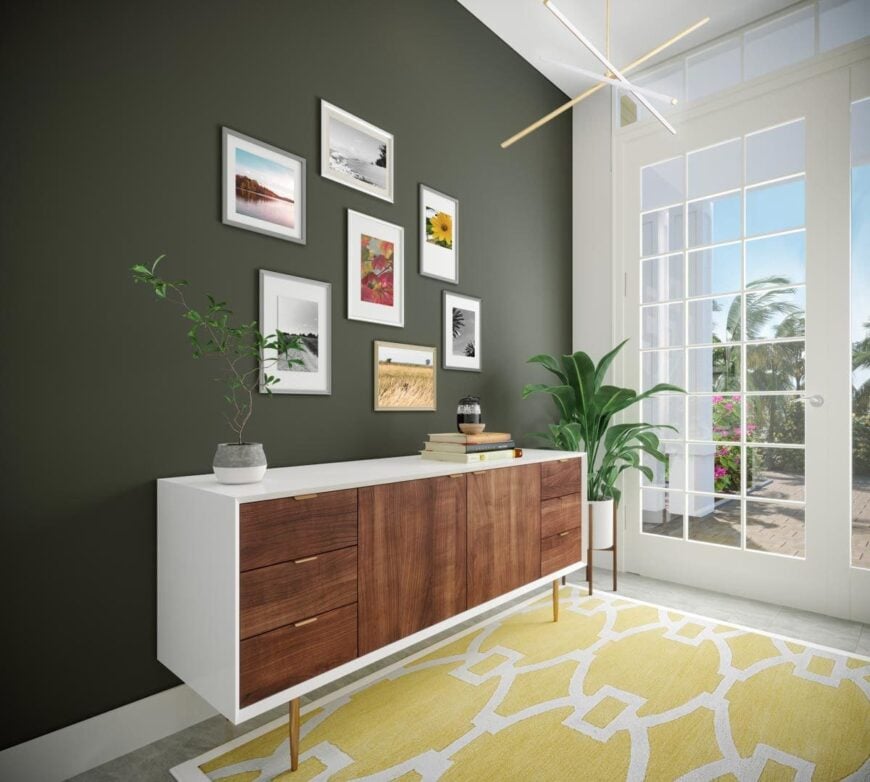 A photo gallery hangs above the wooden console table that sits on a yellow patterned rug.