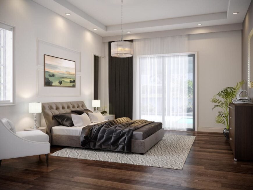 This bedroom features a sleek upholstered bed complemented with a drum chandelier and white cushioned chair.