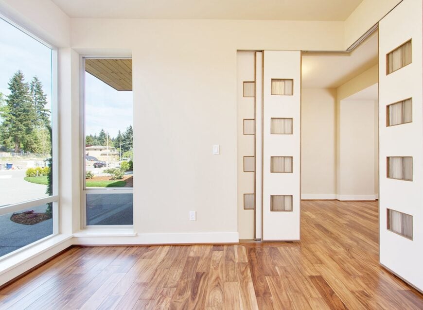 Bright den with beige walls and massive windows that bring an abundance amount of natural light in.