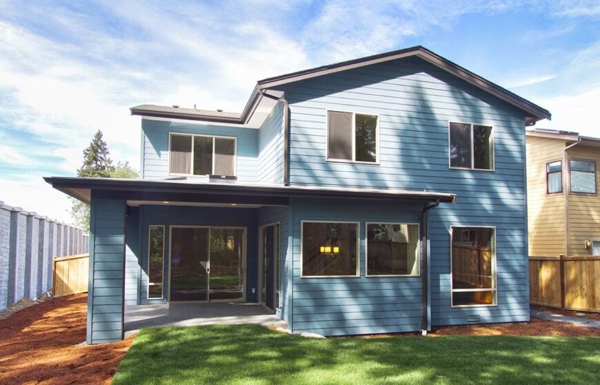 Rear exterior view showing the blue horizontal siding and a covered porch.