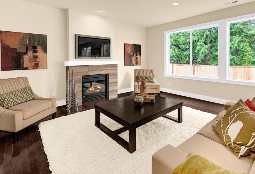 Living room with beige seats, a dark wood coffee table, and a glass-enclosed fireplace with a wall-mounted TV on top.