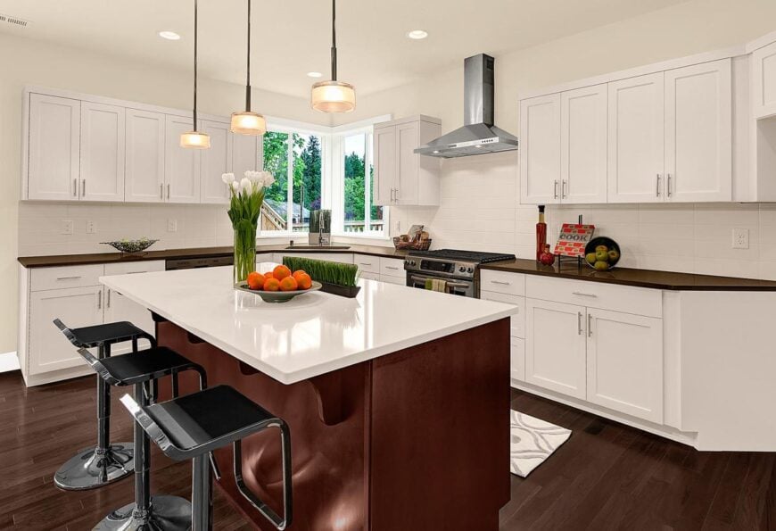 The kitchen offers white cabinetry, stainless steel appliances, and a quartz top island paired with modern bar stools.