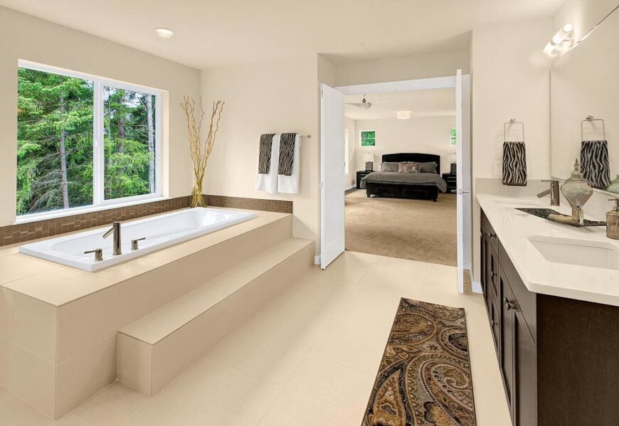 The primary bathroom is equipped with a drop-in bathtub and a dual sink vanity complemented with a patterned runner.