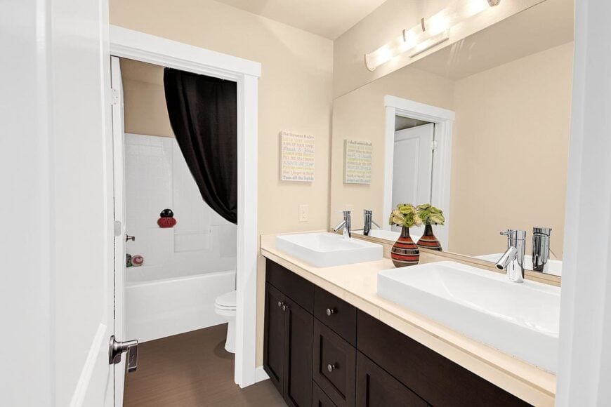 This bathroom offers a dual vessel sink vanity, a toilet, and a tub and shower combo.