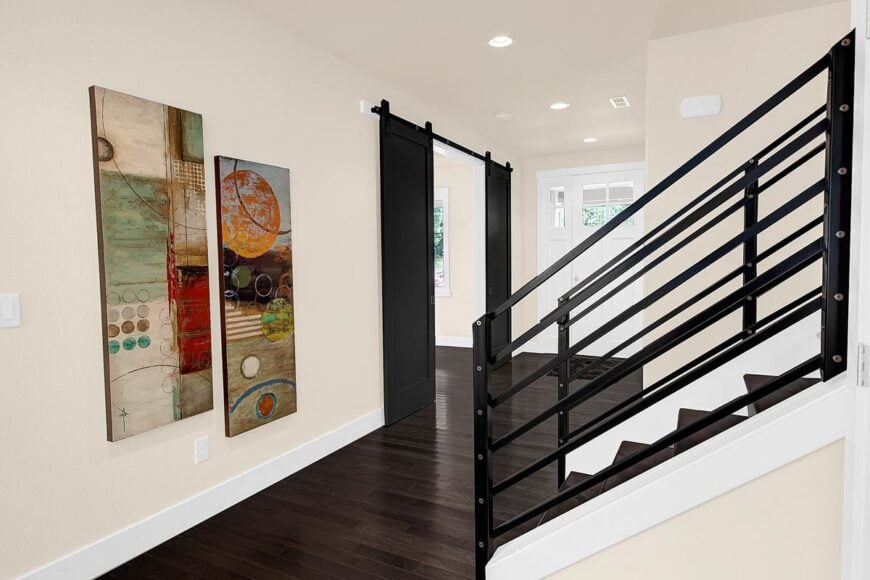Entry hall with a white front door and a pair of striking artworks adorning the beige wall. The large barn door on the side leads to the formal dining room.