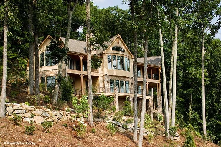 The rear exterior view shows the sloping lot and towering trees that provide privacy to the house.