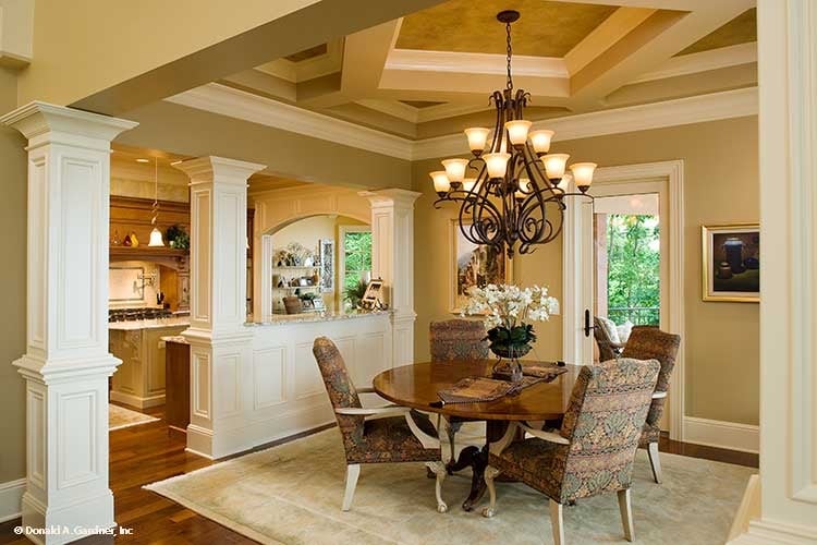 Dining area with patterned upholstered chairs, a round dining table, and an ornate chandelier that hangs from the decorative tray ceiling.