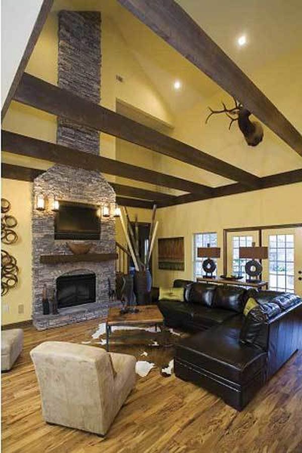 The living room offers an L-shaped leather sofa, beige armchairs, a stone fireplace, and wall-mounted TV.