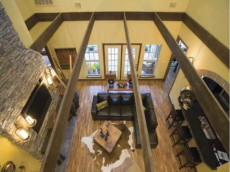 Top view of the living room showing the exposed rustic beams and hardwood flooring topped by a cowhide rug.