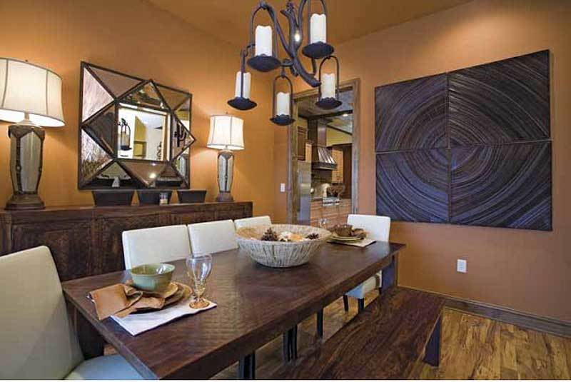 The formal dining room has a wooden dining set, a buffet table, and eye-catching artwork and mirror adorning the brown walls.