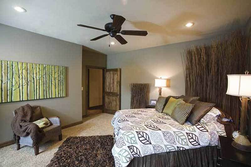 Primary bedroom with gray walls, carpet flooring, and a skirted bed with a custom headboard.