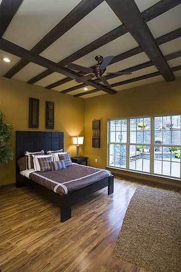 This bedroom offers a beige shaggy rug, a black bed, and white framed windows that invite natural light in.