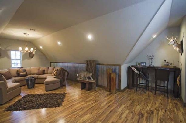 The bonus room has a vaulted ceiling, a curved sectional sofa, and a dark wood desk.