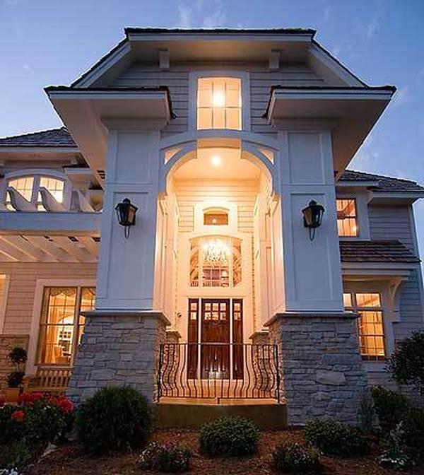 Home's front porch with soaring ceiling and massive columns fitted with wrought iron railings.