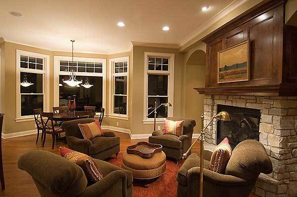 Hearth room with a stone fireplace, black armchairs, and a round ottoman topped with a decorative tray.