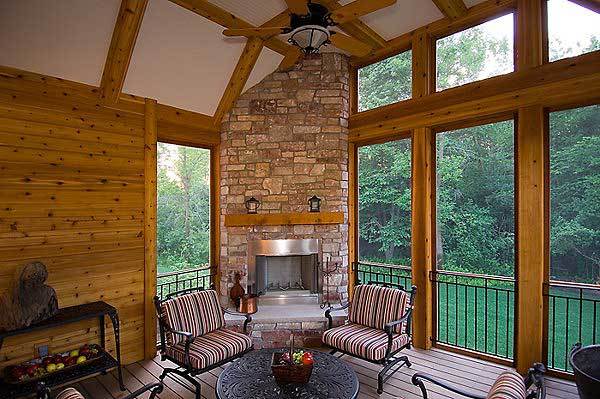 The screened porch offers a corner fireplace and stripe cushioned chairs surrounding the wrought iron center table.